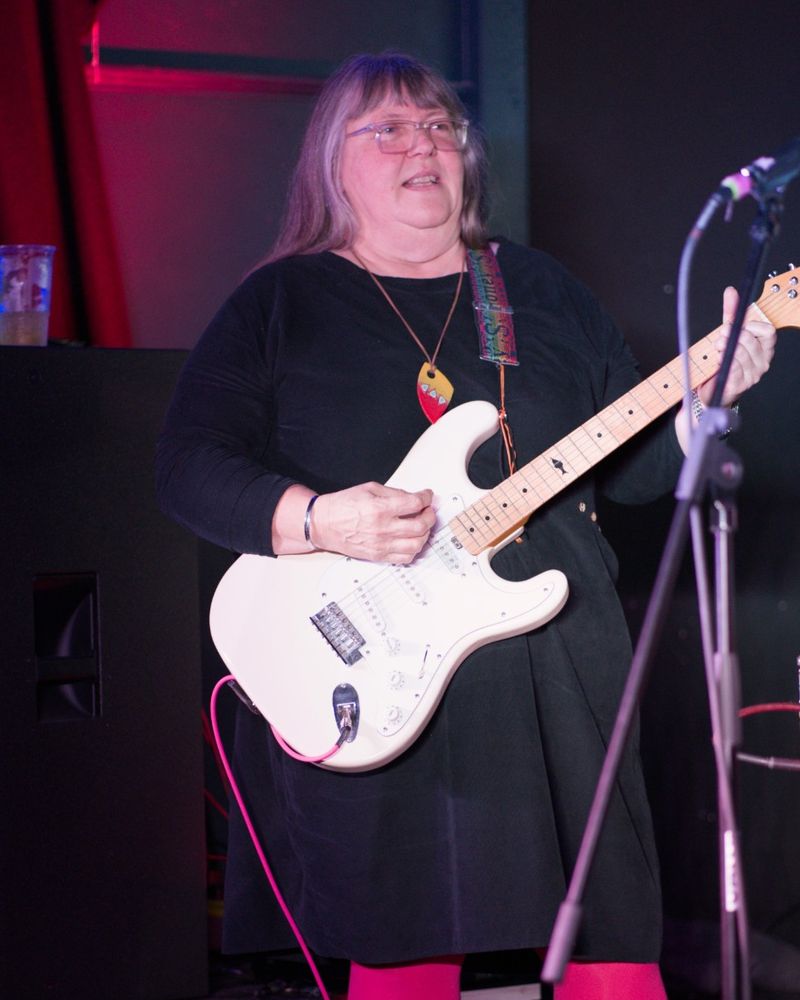 Ange Pearce playing a white guitar on stage