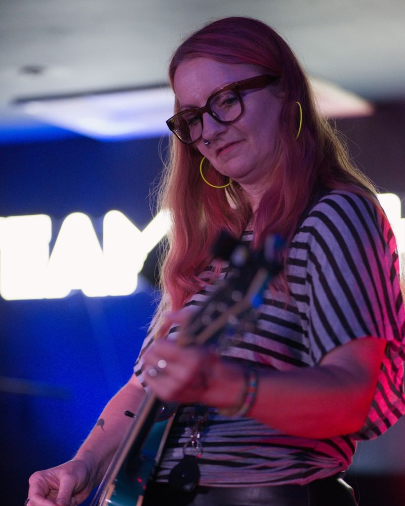 Claire Symons playing a teal guitar on stage