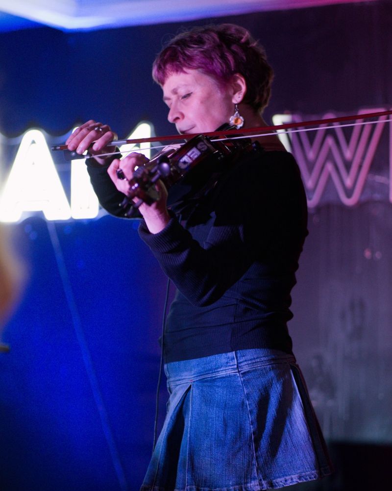 Deb de Lloyd playing an electric viola on stage